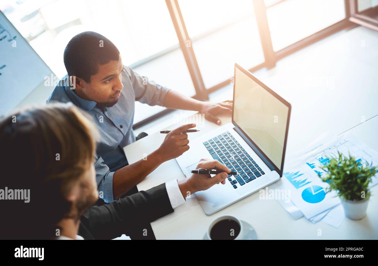 Perfezionare la presentazione. Ripresa ad alta angolazione di due giovani colleghi che utilizzano un notebook insieme in ufficio. Foto Stock