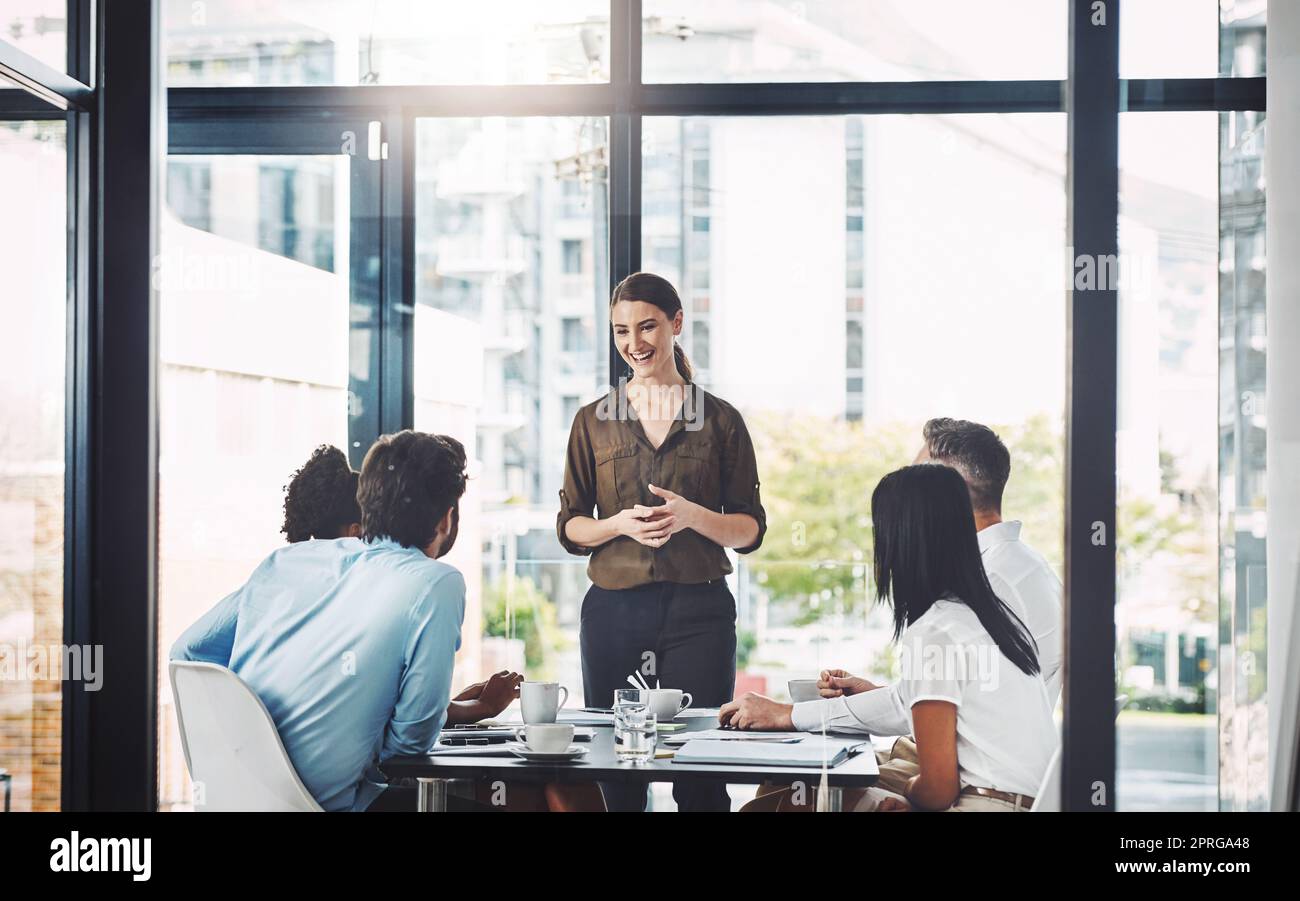 Ci sono alcune opportunità entusiasmanti che ci giungono: Una donna d'affari che presenta i suoi colleghi in una sala riunioni. Foto Stock