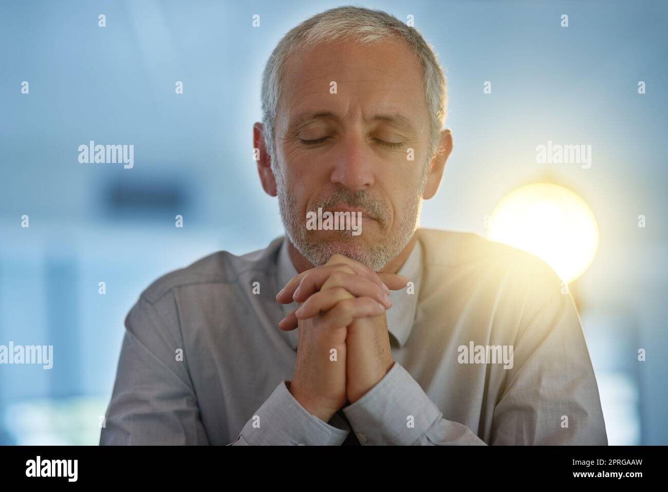 Sperando per il meglio, un uomo d'affari maturo seduto con le mani si stringeva nella preghiera. Foto Stock