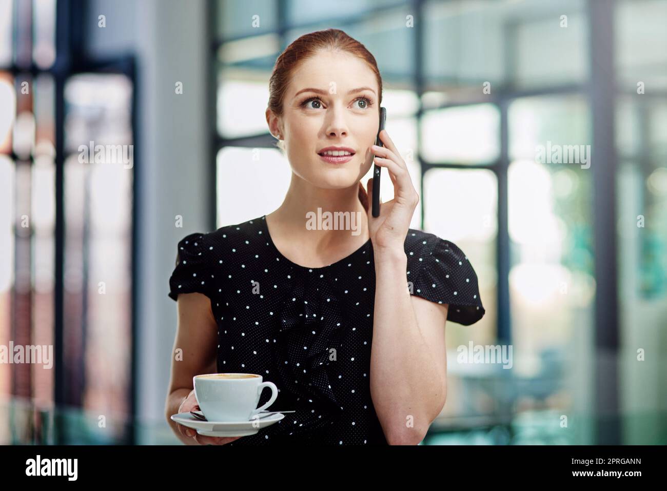 E come posso aiutarla. Una giovane donna d'affari che fa una chiamata sul suo cellulare durante la sua pausa caffè. Foto Stock