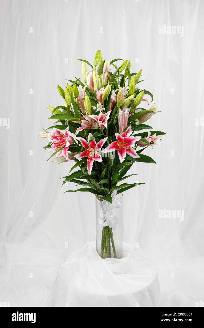 Bel grande bouquet di gigli rosa in vaso di vetro trasparente. Foto Stock