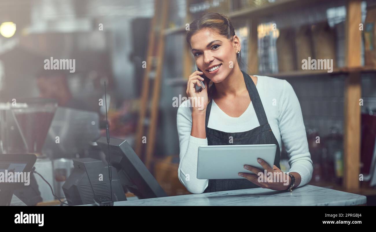 Diffondete la notizia della vostra piccola impresa con la tecnologia moderna. Ritratto di una giovane donna che usa un telefono e un tablet digitale nel negozio in cui lavora. Foto Stock