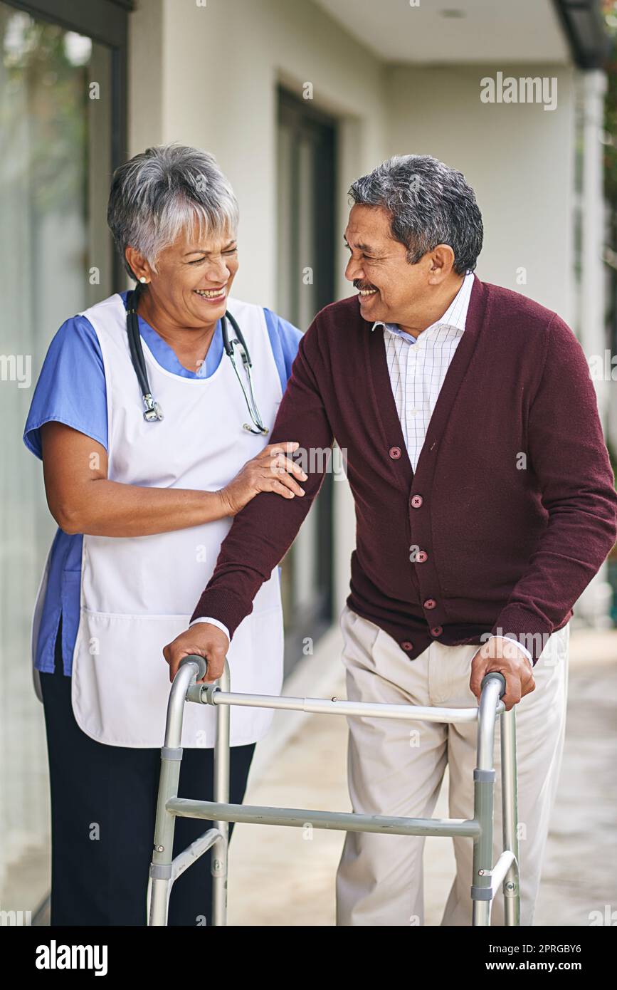 Fare i passi giusti per un benessere più sano. Un'infermiera che va a camminare con il paziente anziano e il suo camminatore fuori. Foto Stock