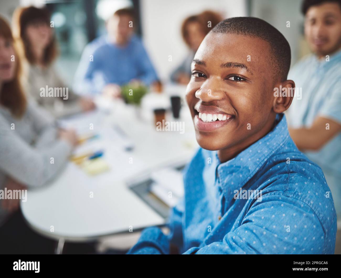 Non sarei niente senza la mia squadra. Ritratto ritagliato di un giovane uomo d'affari che si guarda alle spalle seduto in una sala riunioni con i suoi colleghi. Foto Stock