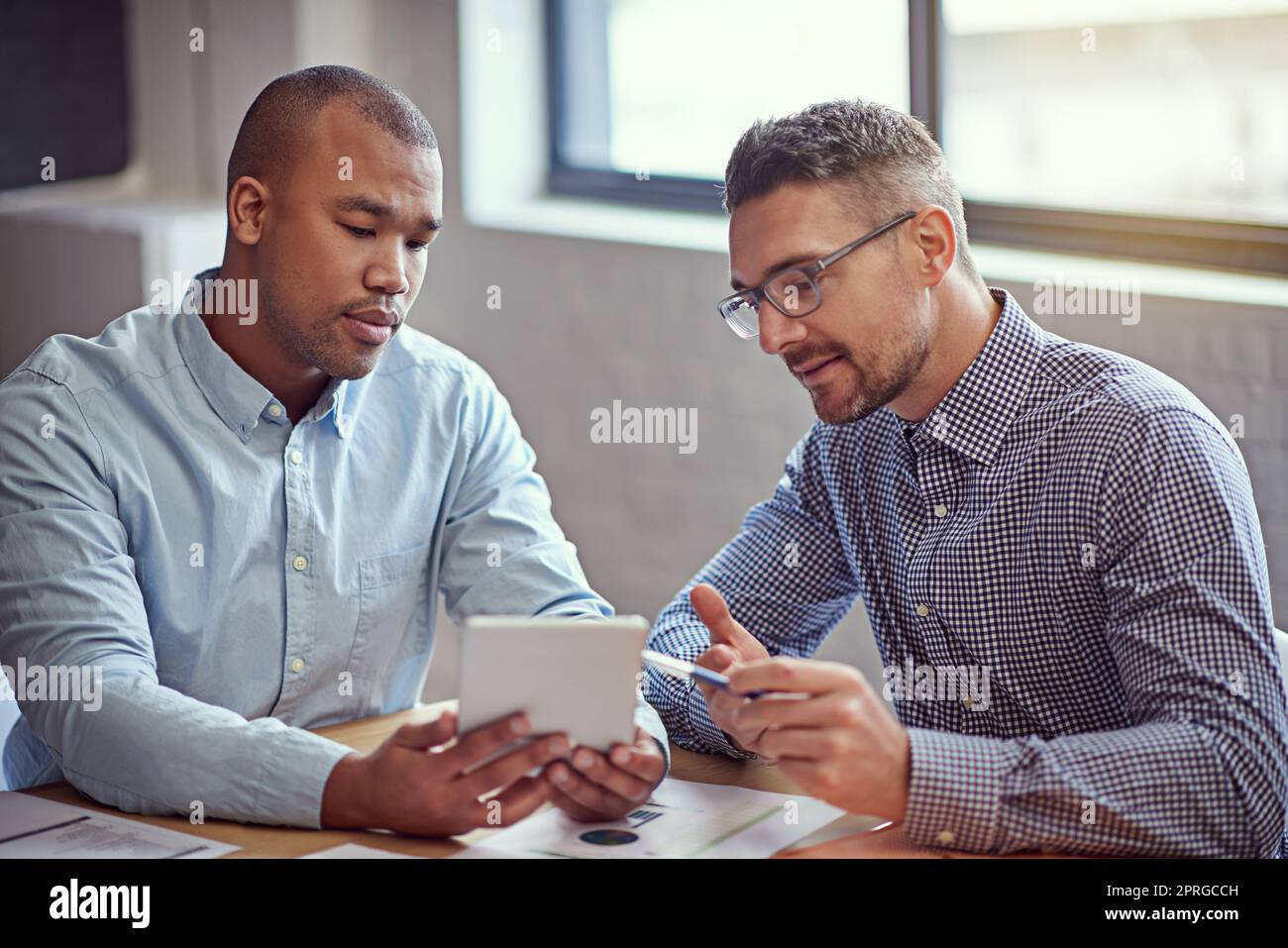 Utilizzare la tecnologia per migliorare la propria attività. Immagine di due designer che lavorano su un tablet digitale in ufficio. Foto Stock