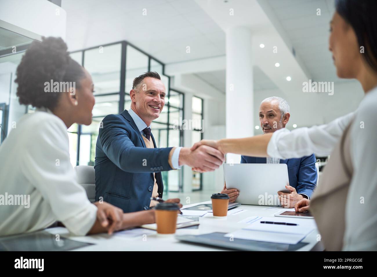 Un caloroso benvenuto a un nuovo membro del personale. Uomini d'affari stringono le mani durante una riunione in un ufficio moderno. Foto Stock