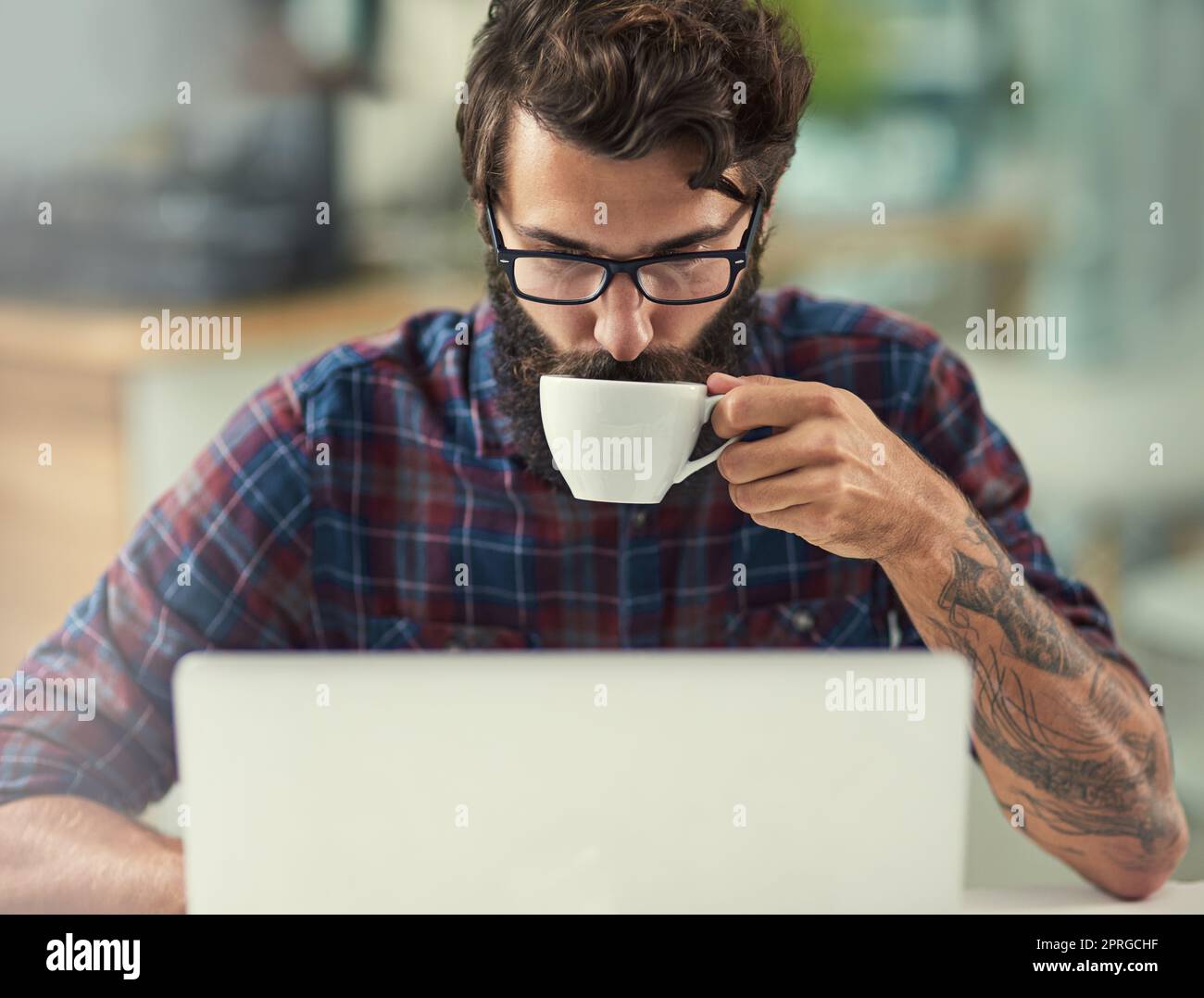 Un sorso di caffè è una meraviglia per la mia creatività. Un designer che ha un caffè mentre lavora sul suo computer portatile. Foto Stock