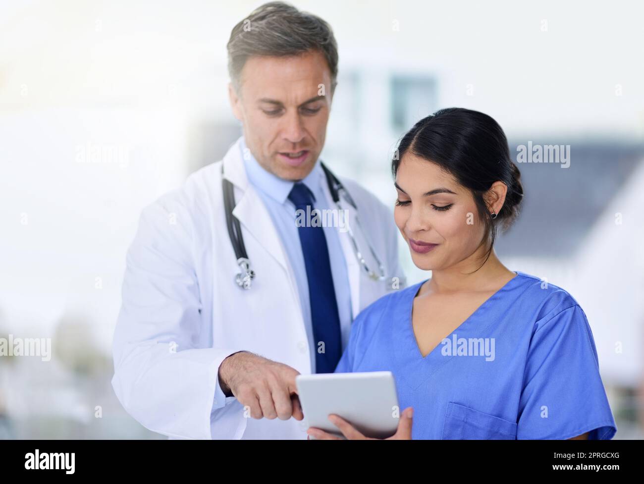Decidere il trattamento più efficace per il loro paziente. Medici che guardano un paziente cartella su un tablet digitale. Foto Stock