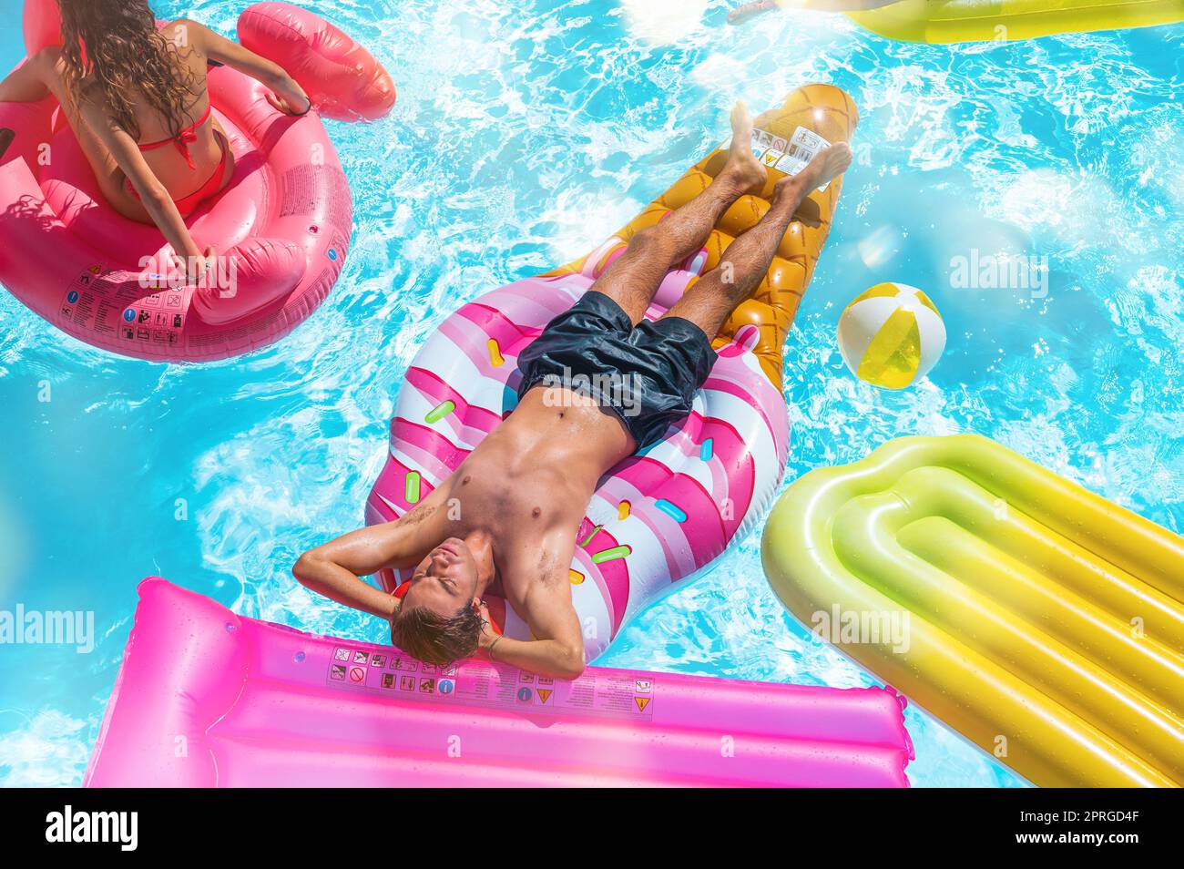 Gli amici in costume da bagno in piscina si abbronzano Foto Stock