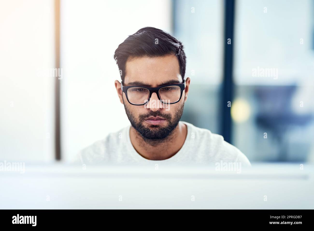 Si è concentrato sul suo lavoro, un giovane che lavora nel suo ufficio. Foto Stock