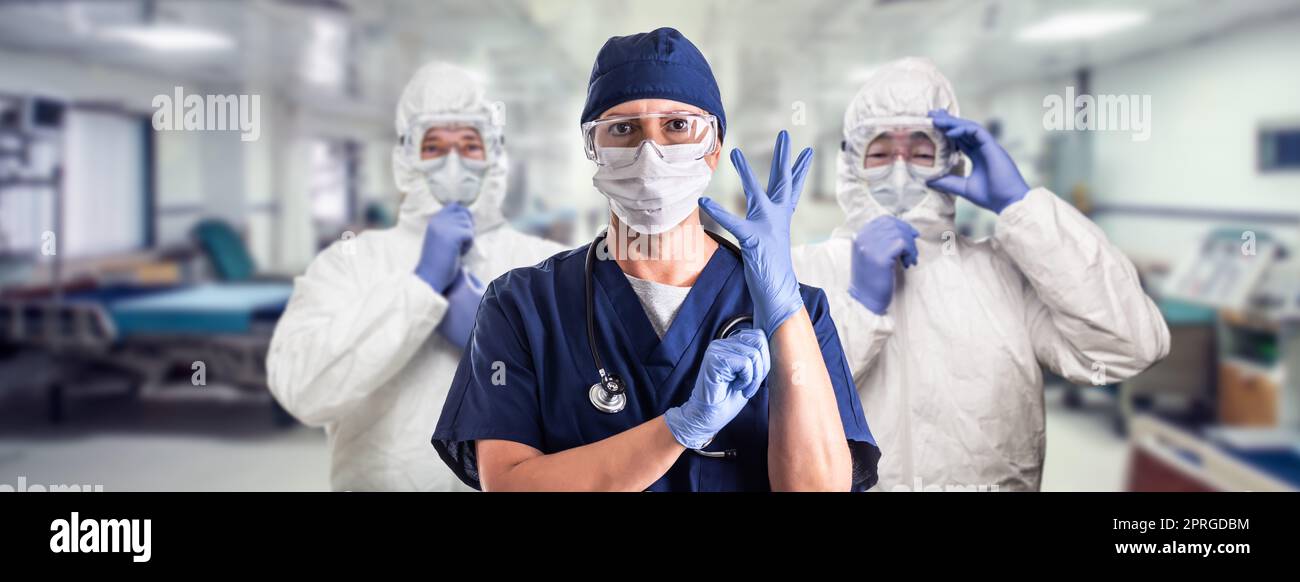 Team di medici o infermieri femminili e maschili che indossano un equiment protettivo personale nella stanza di emergenza ospedaliera. Foto Stock