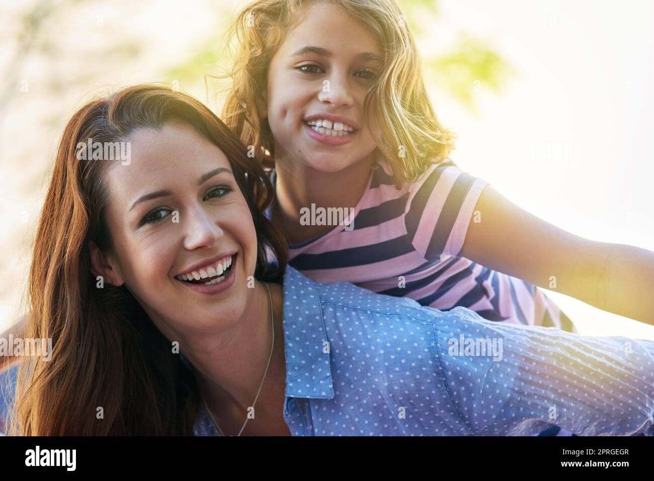 Il nostro tempo insieme è un dono: Una madre che dà a sua figlia un giro in piggyback. Foto Stock