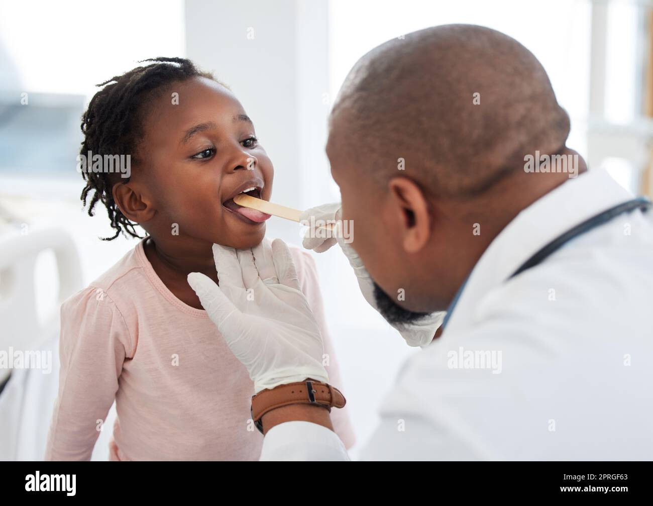 Bambini medico, lingua e gola esame in ospedale sanitario, sala benessere e clinica di consulenza medica. Lavoratore, dipendente e uomo di medicina con fiducia e sostegno per le ragazze nell'analisi della bocca covid-19 Foto Stock