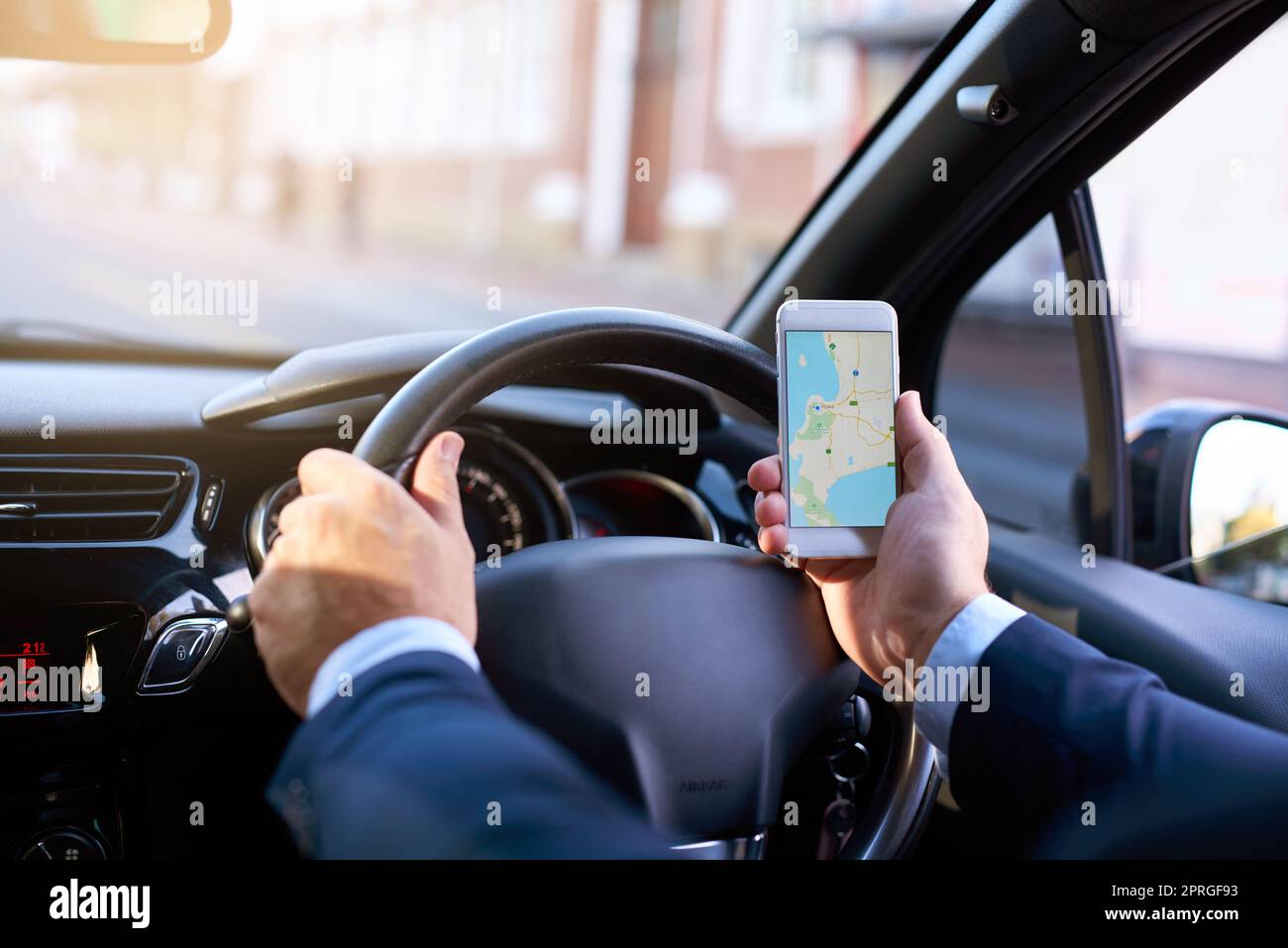 In contatto con il suo viaggio. Un uomo d'affari irriconoscibile che usa il suo cellulare durante la guida. Foto Stock