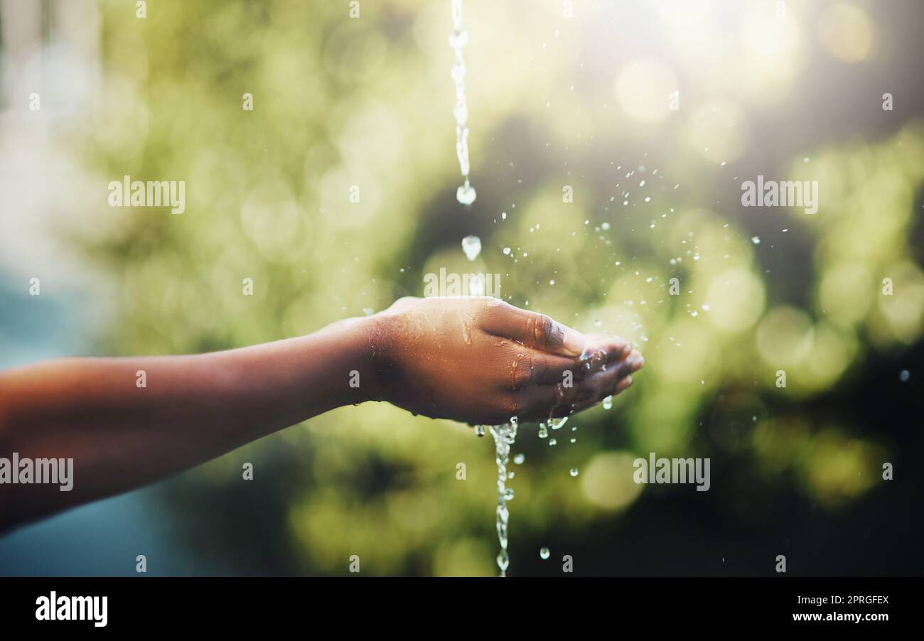 L'acqua è la chiave della vita. Mani tenute fuori per prendere un flusso di acqua fuori. Foto Stock