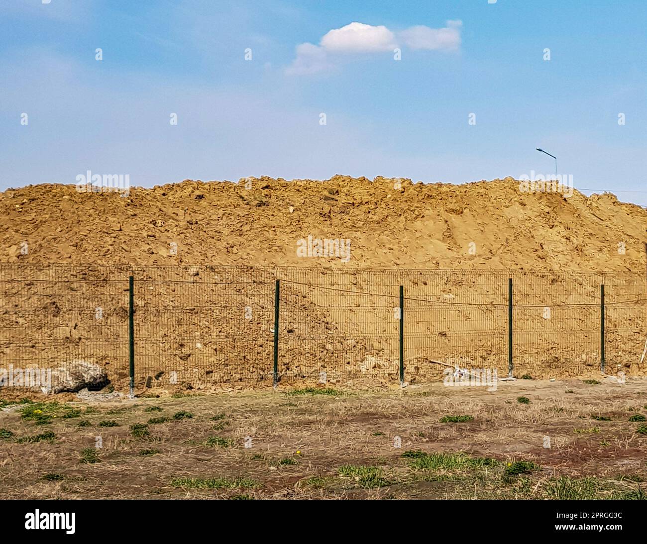 Lavori in terra all'aperto con un grande cumulo di sabbia dietro la recinzione e un paesaggio paradisiaco Foto Stock