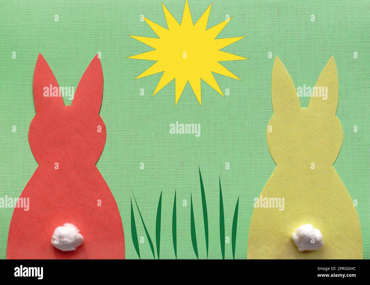 Un coniglietto di carta rosso e un coniglietto di carta giallo su sfondo verde con sole ed erba illustrate Foto Stock