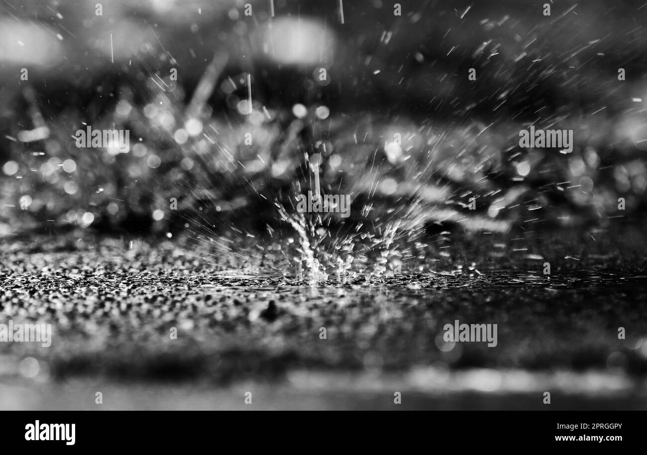 In caso di pioggia intensa, le grandi gocce cadono a terra con una cravatta nera Foto Stock
