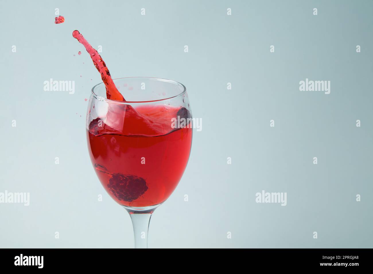 raspberry spruzzi in un bicchiere di vino succo rosso bevanda spruzzi d'acqua goccia su sfondo bianco Foto Stock