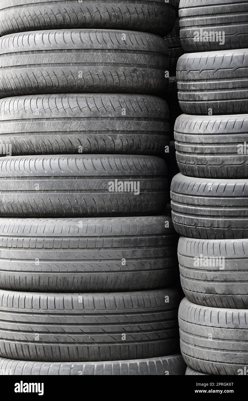Vecchi pneumatici usati impilati con pali alti nel secondario di parti per auto shop garage vicino fino Foto Stock