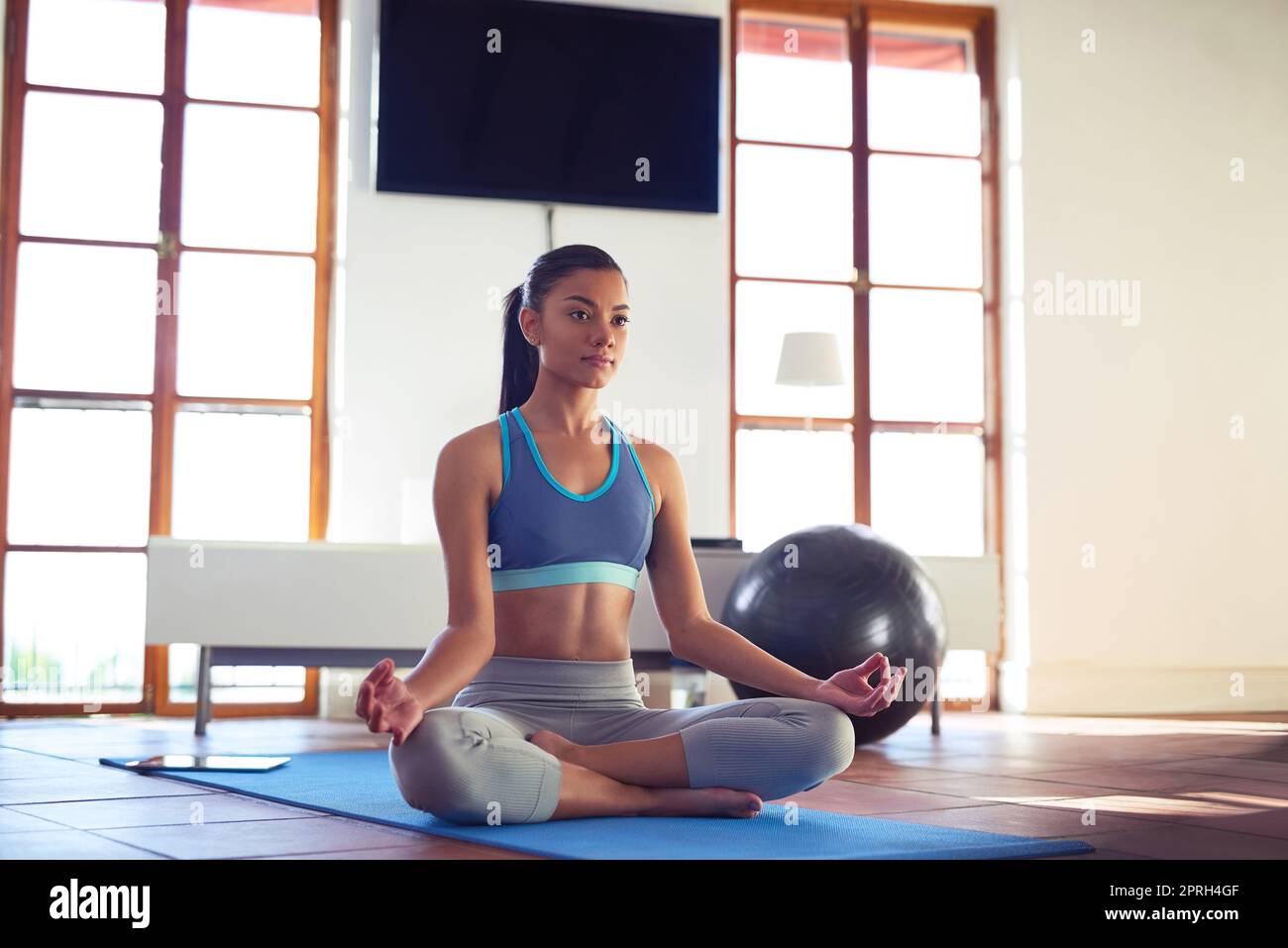 La pace nasce dall'interno: Una giovane donna medita mentre fa yoga a casa. Foto Stock