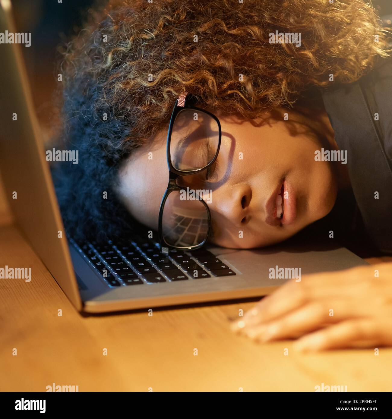 Scalare la scala del successo può essere faticoso. Una giovane donna d'affari che dorme sul suo laptop mentre lavora tardi in ufficio. Foto Stock