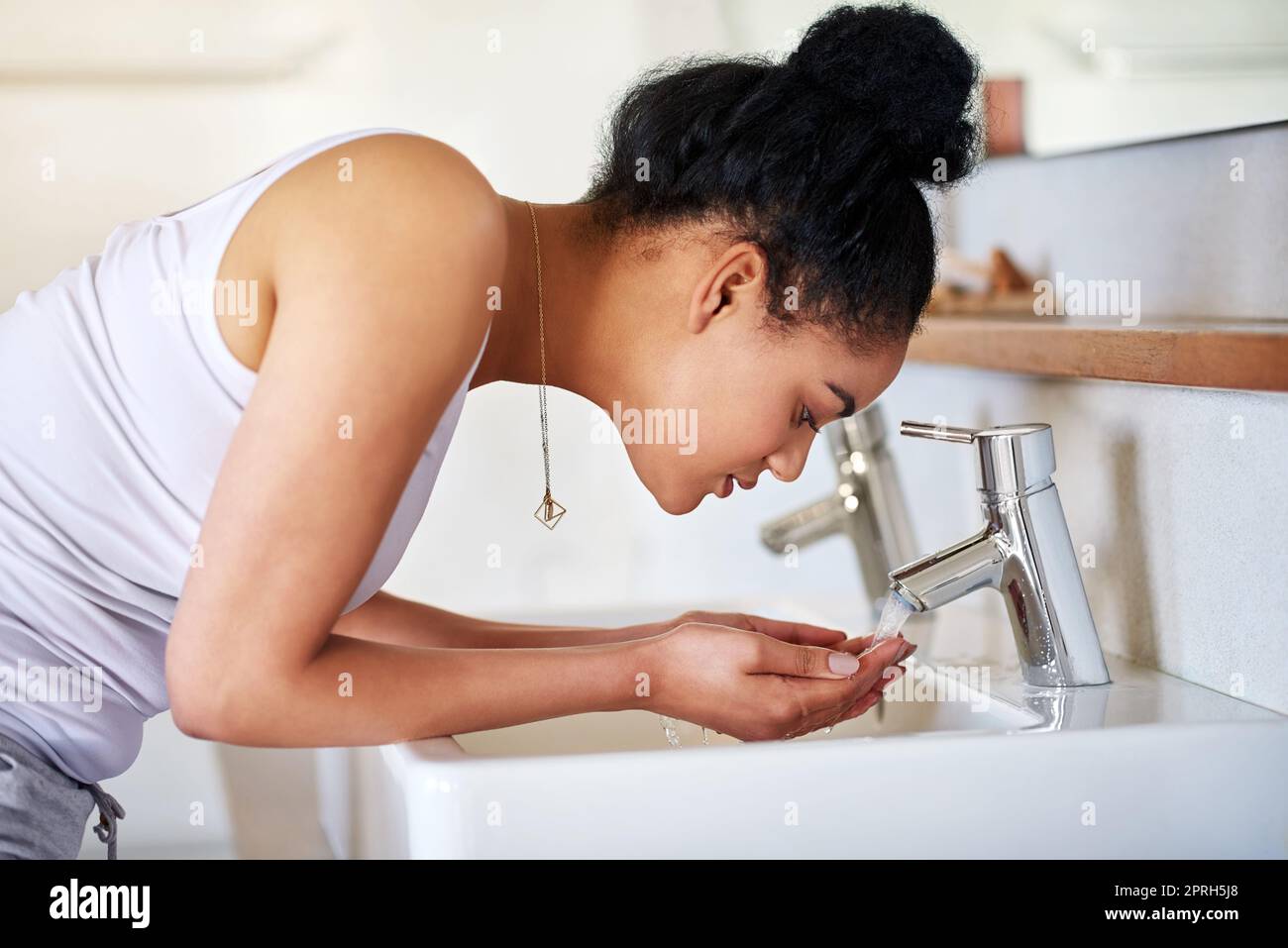 Una pelle sana è una scelta. Una giovane donna che si lava il viso al lavandino del bagno. Foto Stock