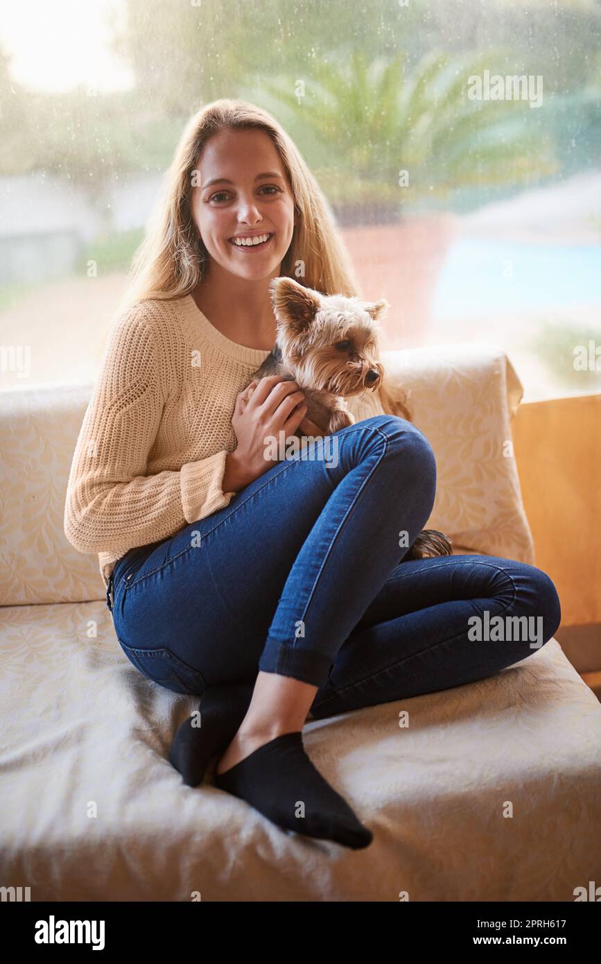 HES il meglio dei migliori amici. Ritratto di una giovane donna attraente e il suo cucciolo seduto sul divano a casa. Foto Stock