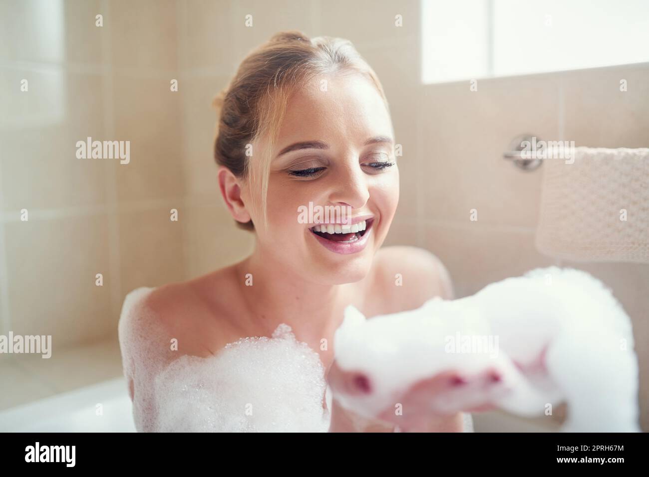 I bagni di bolla sono il mio genere perfetto di sollievo di sforzo. Una giovane donna attraente che si rilassa nella vasca da bagno. Foto Stock