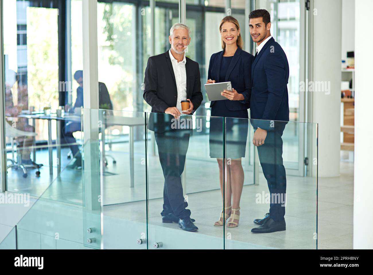 Stavano avvicinando il futuro dell'azienda. Ritratto a figura intera di un gruppo di giovani imprenditori in piedi insieme in un ufficio moderno e utilizzando un tablet. Foto Stock