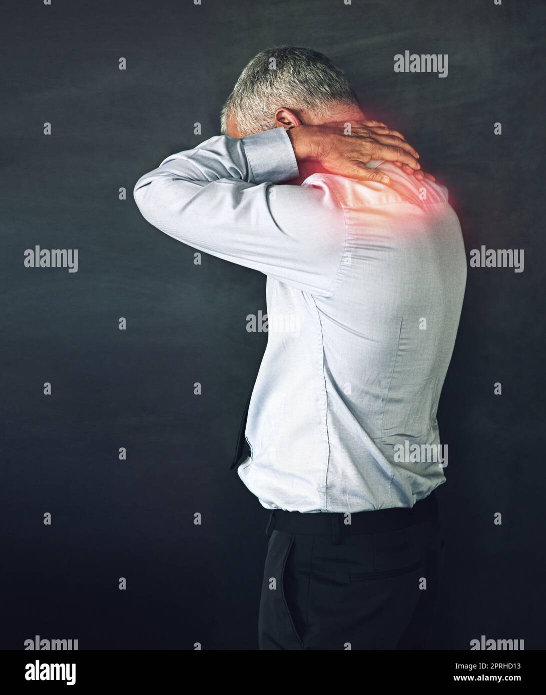 Quando lo stress da lavoro diventa fisico. Studio shot di un uomo maturo che sperimenta dolore al collo su uno sfondo nero. Foto Stock