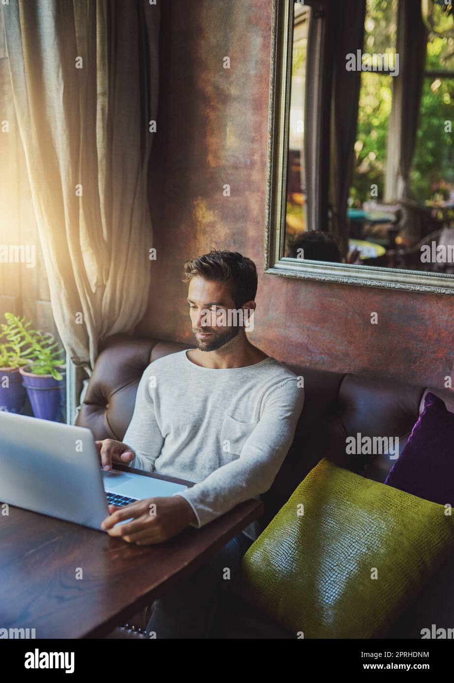 Leggere un articolo online. Un giovane uomo che usa il suo computer portatile in una caffetteria. Foto Stock