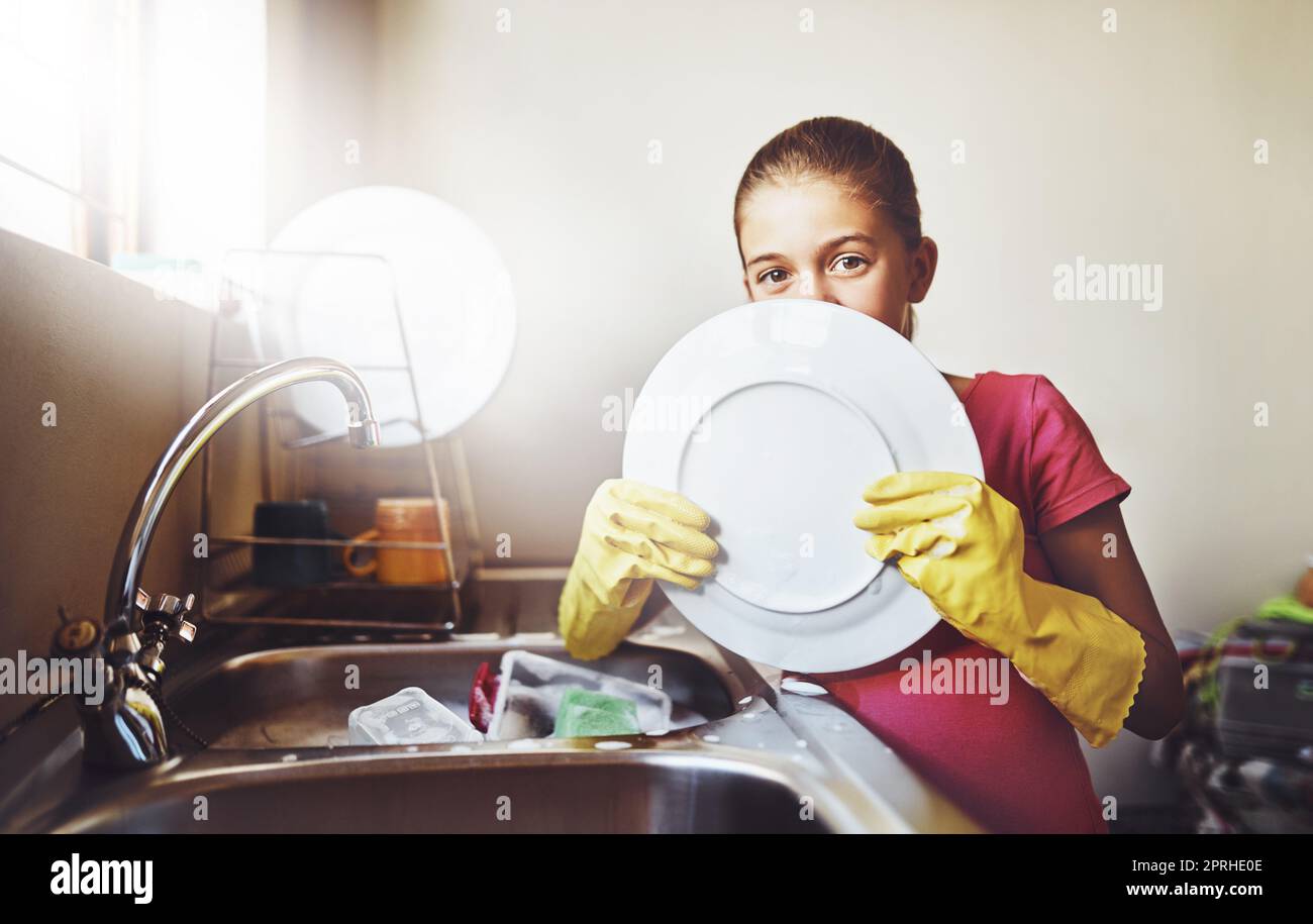 Pulizia stridula. Ritratto di una giovane ragazza allegra lavare piatti con guanti gialli a casa mentre si guarda la macchina fotografica. Foto Stock