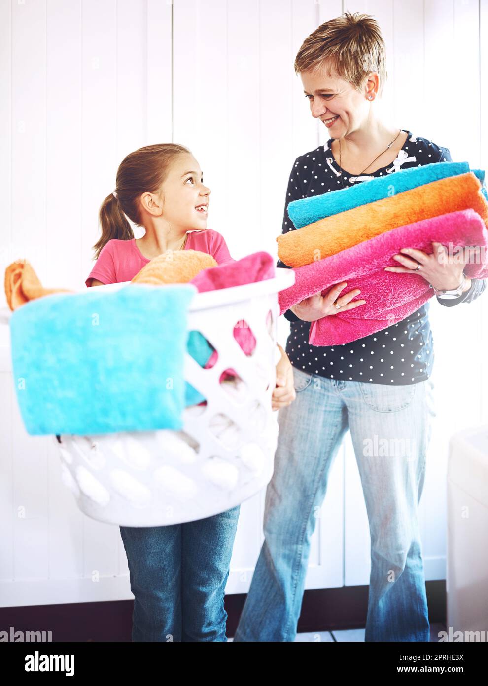 Facciamo la mamma migliore della squadra. Una madre e una figlia allegre ciascuno tenendo un mucchio di asciugamani appena lavati mentre si guardano a casa. Foto Stock