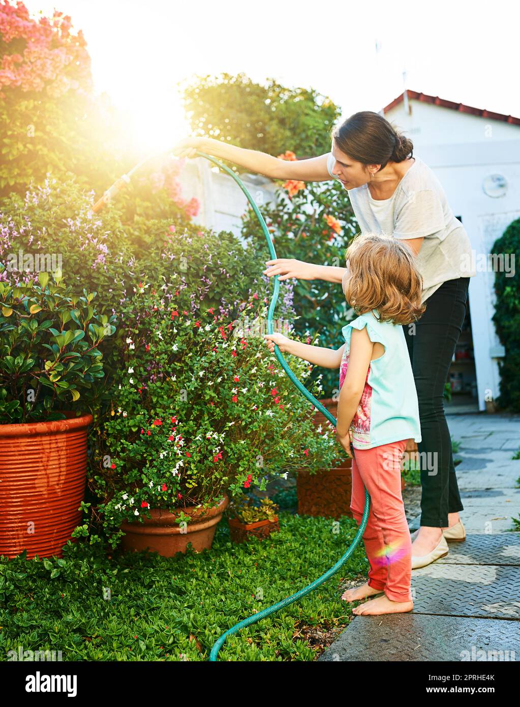 Prendersi cura del giardino è il suo lavoro ora. Una madre e una figlia che fanno le faccende insieme a casa. Foto Stock