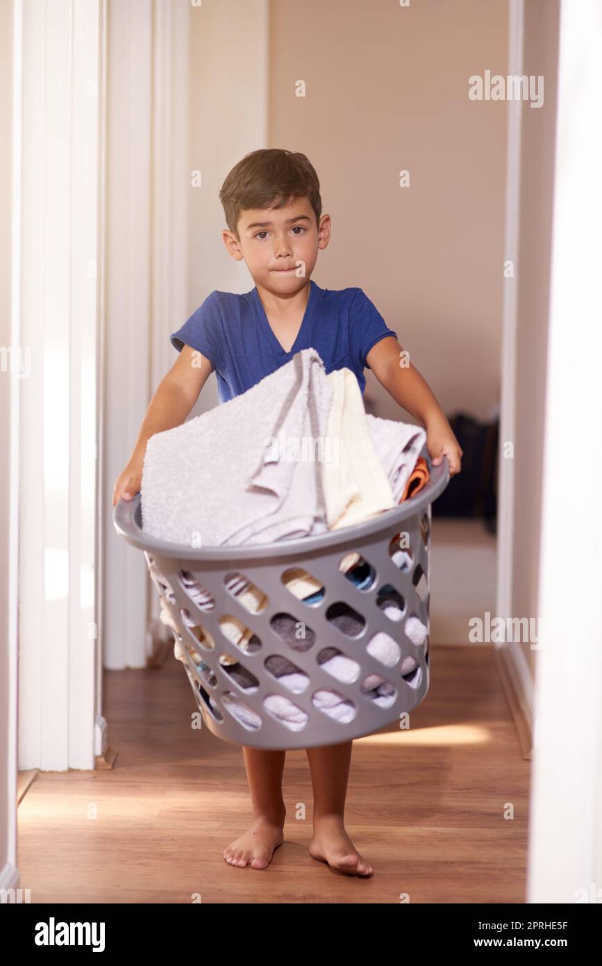 Aiutare fuori intorno alla casa. Ritratto di un ragazzino che tiene un cesto di bucato a casa. Foto Stock