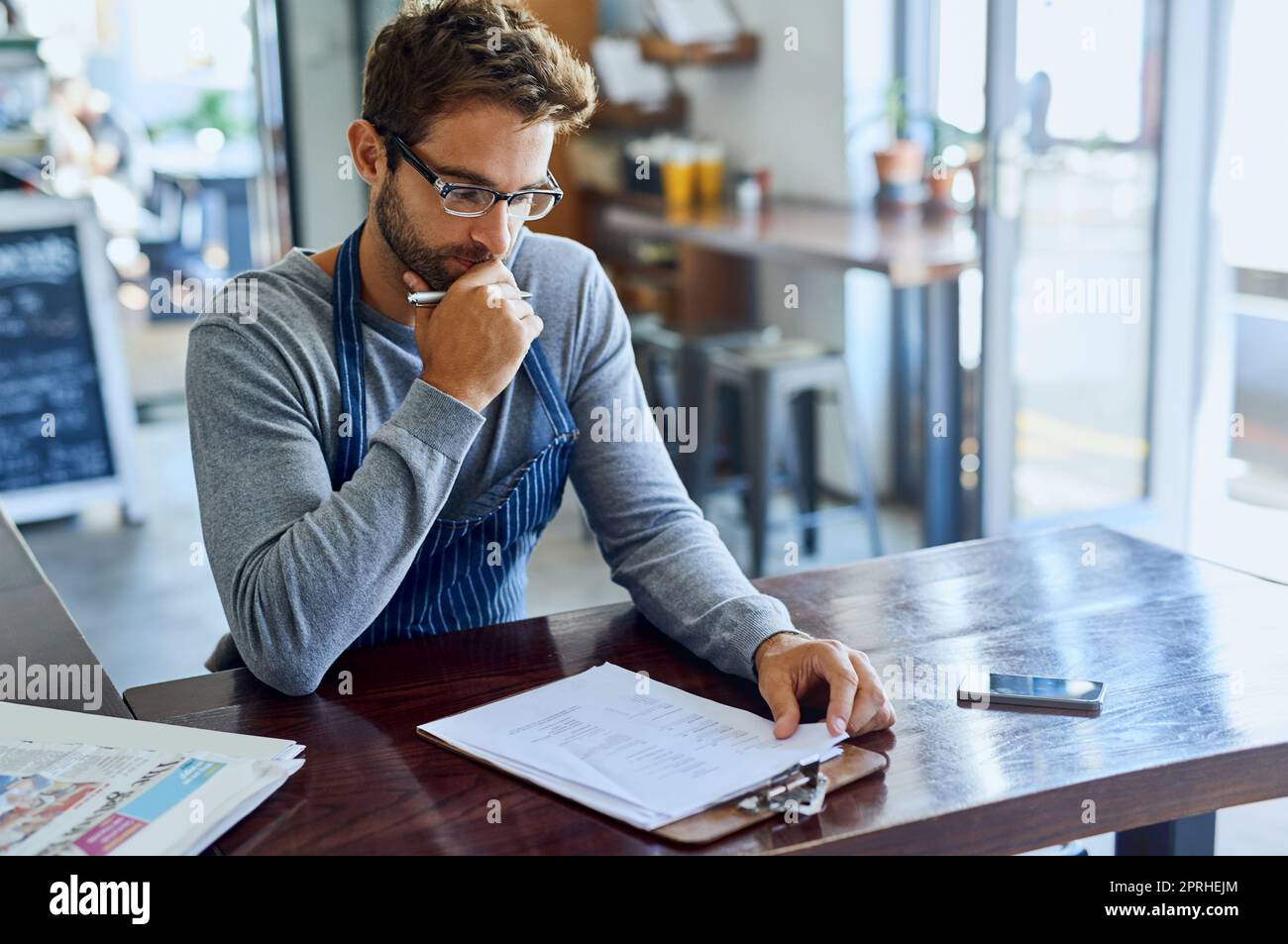 Il duro lavoro che ha reso la sua piccola impresa un successo. Un bel giovane proprietario della caffetteria che ha superato la documentazione. Foto Stock