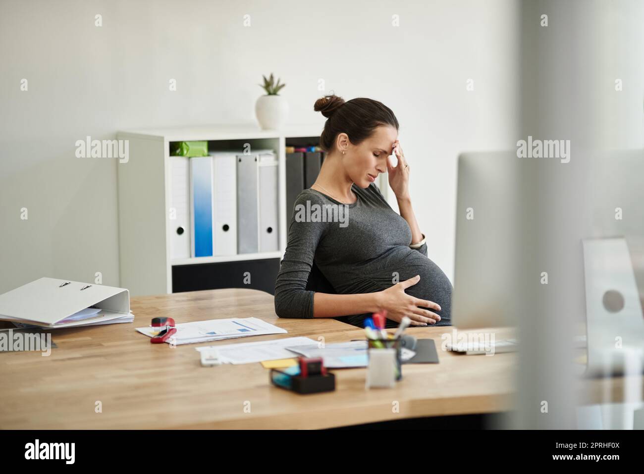 Oggi era estenuante. Una donna d'affari incinta in disagio nel suo ufficio. Foto Stock