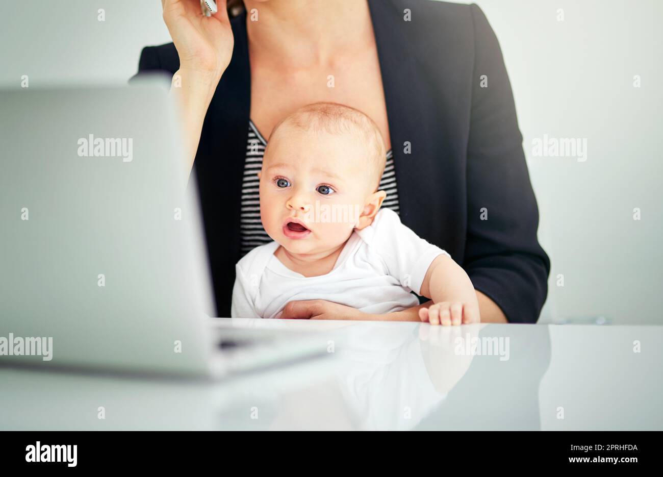 Ecco dove va tutto il mio tempo libero. Una donna d'affari che si occupa del bambino mentre lavora sul suo laptop. Foto Stock