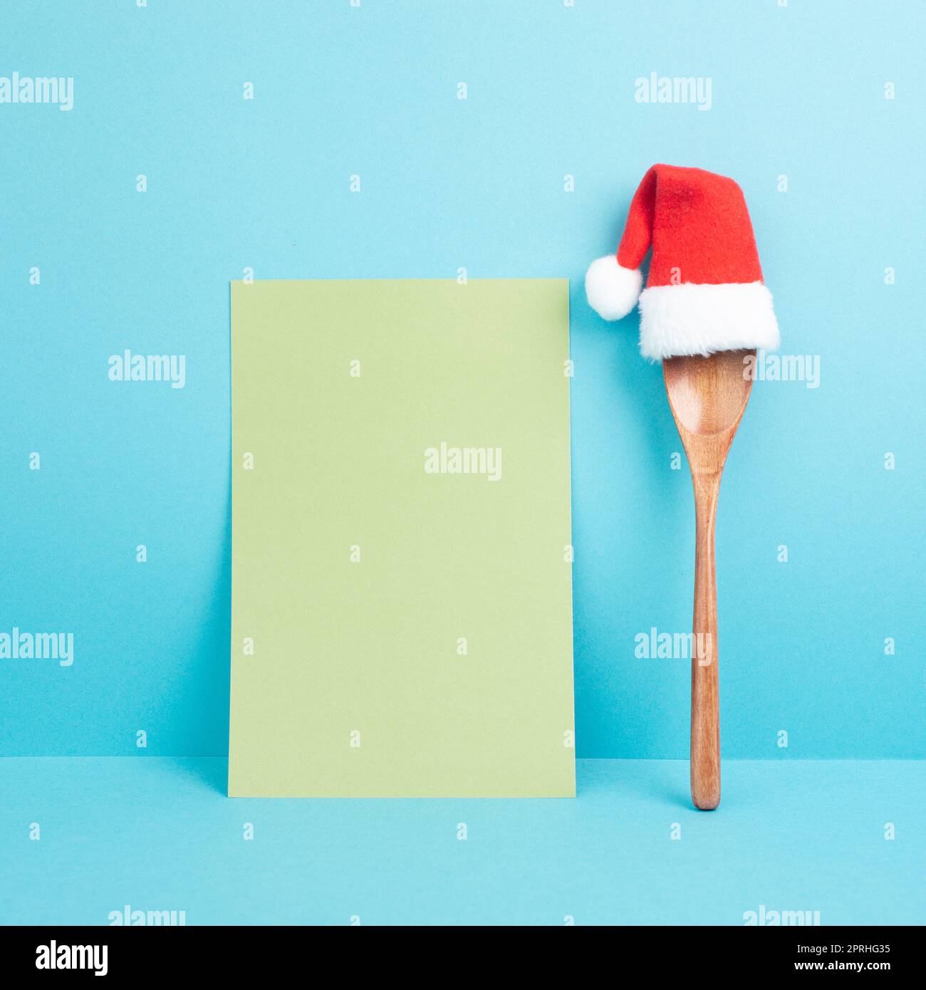Carta bianca con un cucchiaio di legno e un cappello rosso di Babbo Natale, biglietto di auguri di natale, spazio copia per una ricetta per le vacanze Foto Stock