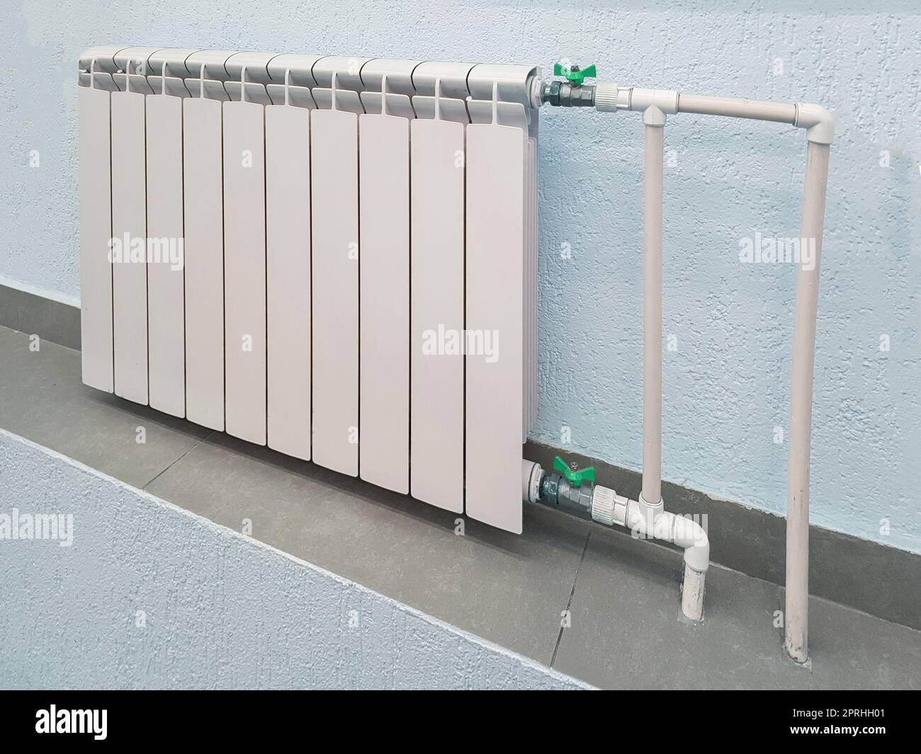 Batteria bianca per radiatore in alluminio moderno per riscaldamento ad acqua calda, sullo sfondo di una parete all'interno di un appartamento o di un ufficio Foto Stock