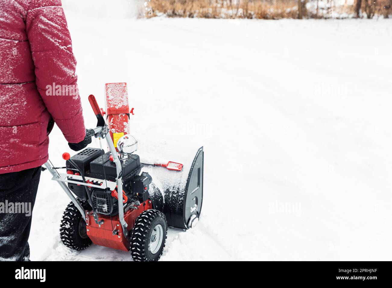 Particolare della soffiatrice portatile di neve rossa alimentata a benzina in azione. Uomo all'aperto che usa una macchina spazzaneve dopo la tempesta di neve. Rimozione neve, lanciatore assestan Foto Stock