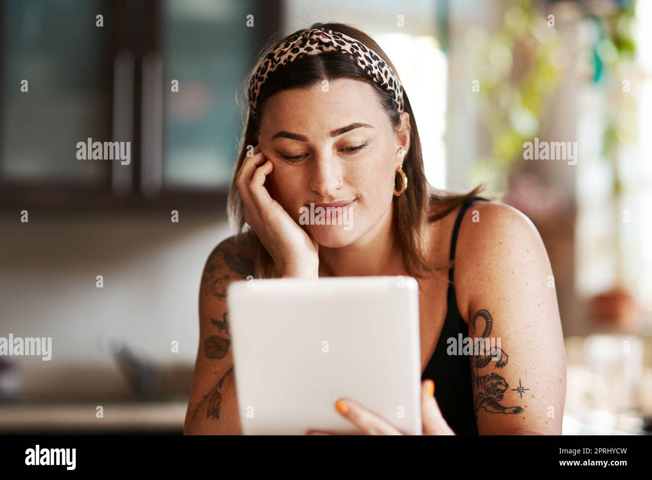 Alcuni post parlano solo con voi. una giovane donna che usa un tablet digitale in cucina a casa Foto Stock