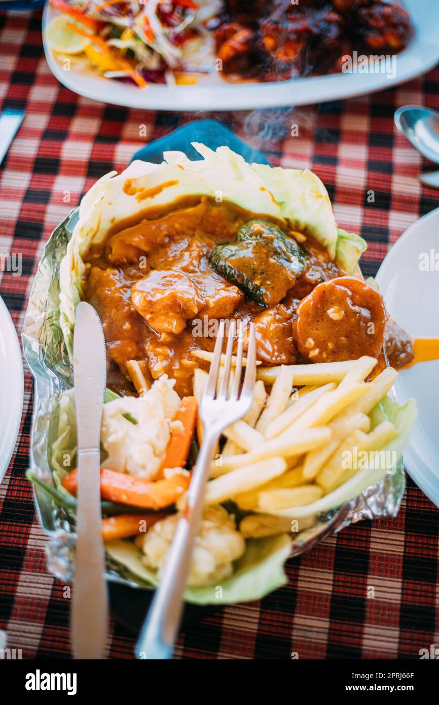 Goa, India. Il piatto della cucina nazionale indiana è il Sizzler, composto da patatine fritte, gamberi fritti in salsa e verdure fritte. Piatto tradizionale di Goa Foto Stock