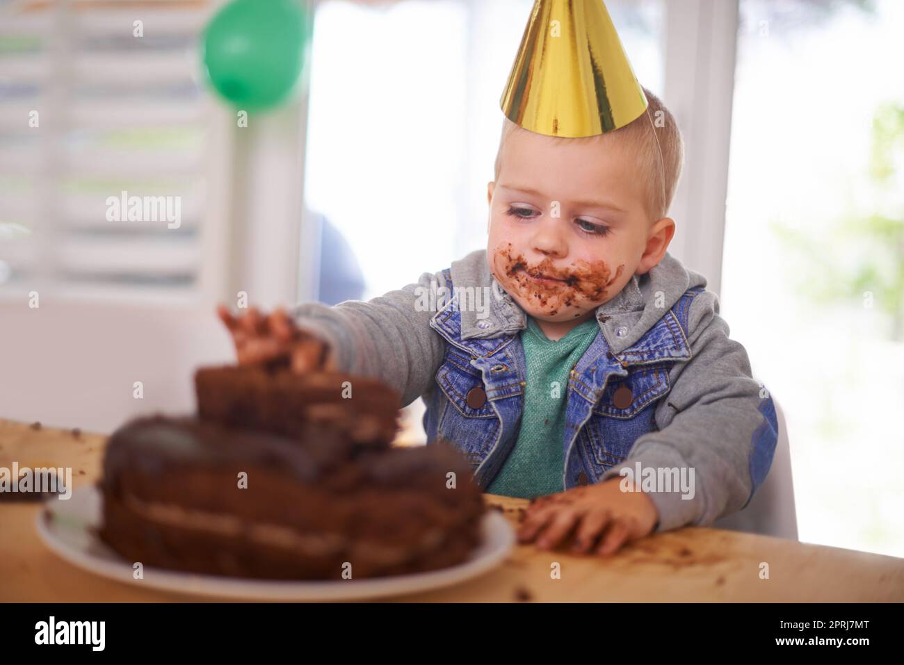 Quella torta non ha mai avuto una possibilità: Un ragazzo che mangiava la torta di compleanno prima della festa Foto Stock