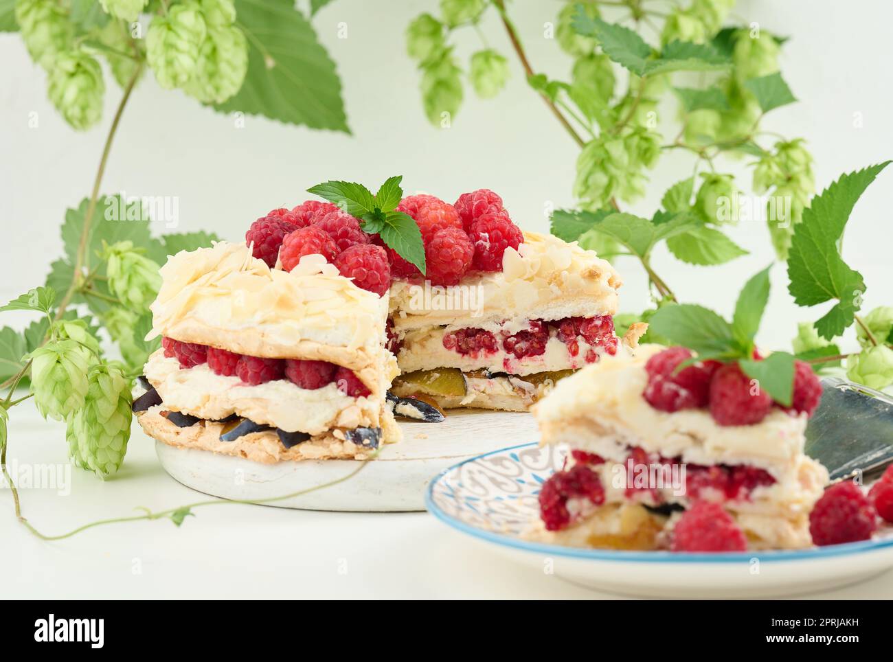 Torta di meringa rotonda con lamponi freschi su sfondo bianco, Pavlova dessert Foto Stock