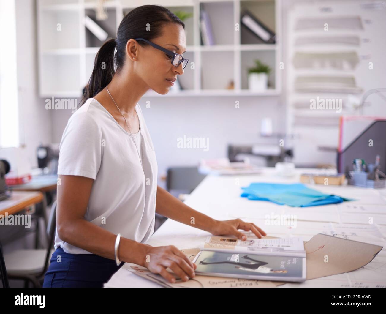 Guardando oltre il suo primo articolo di moda. Un giovane stilista al lavoro Foto Stock