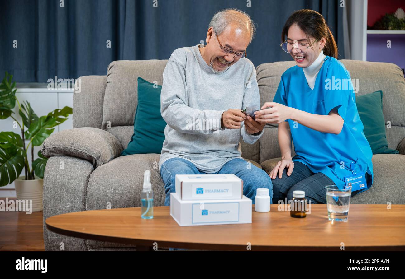 Donna infermiera che mostra il farmaco di prescrizione all'uomo anziano a casa di cura Foto Stock