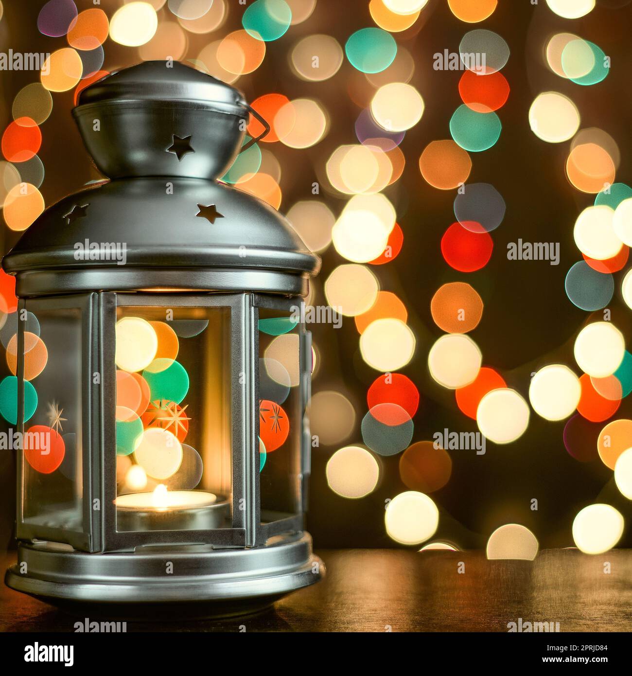 Cartolina di Natale: lanterna con candele e luci sfocate sullo sfondo. Foto Stock