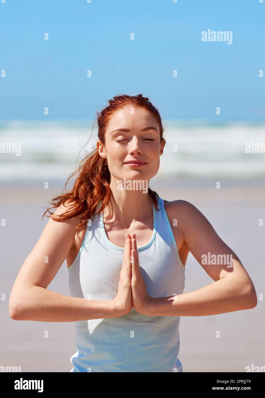 Mi incontro in quiete, e respiriamo: Una giovane donna che pratica la sua routine di yoga in spiaggia. Foto Stock